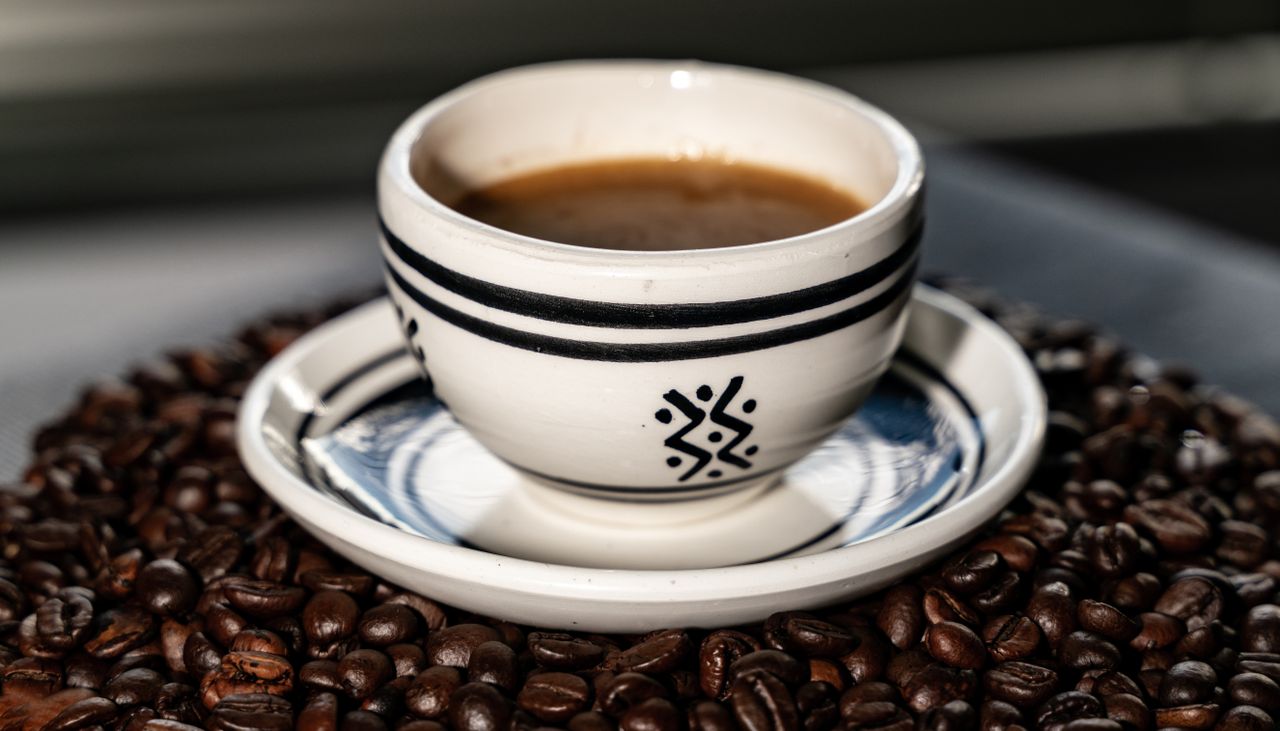 home-hero Artisan coffee served in a decorative ceramic mug surrounded by beans, ideal for cozy cafe vibes.